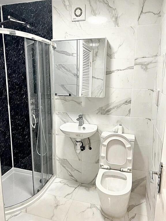 Bright, modern bathroom with a curved glass sho...