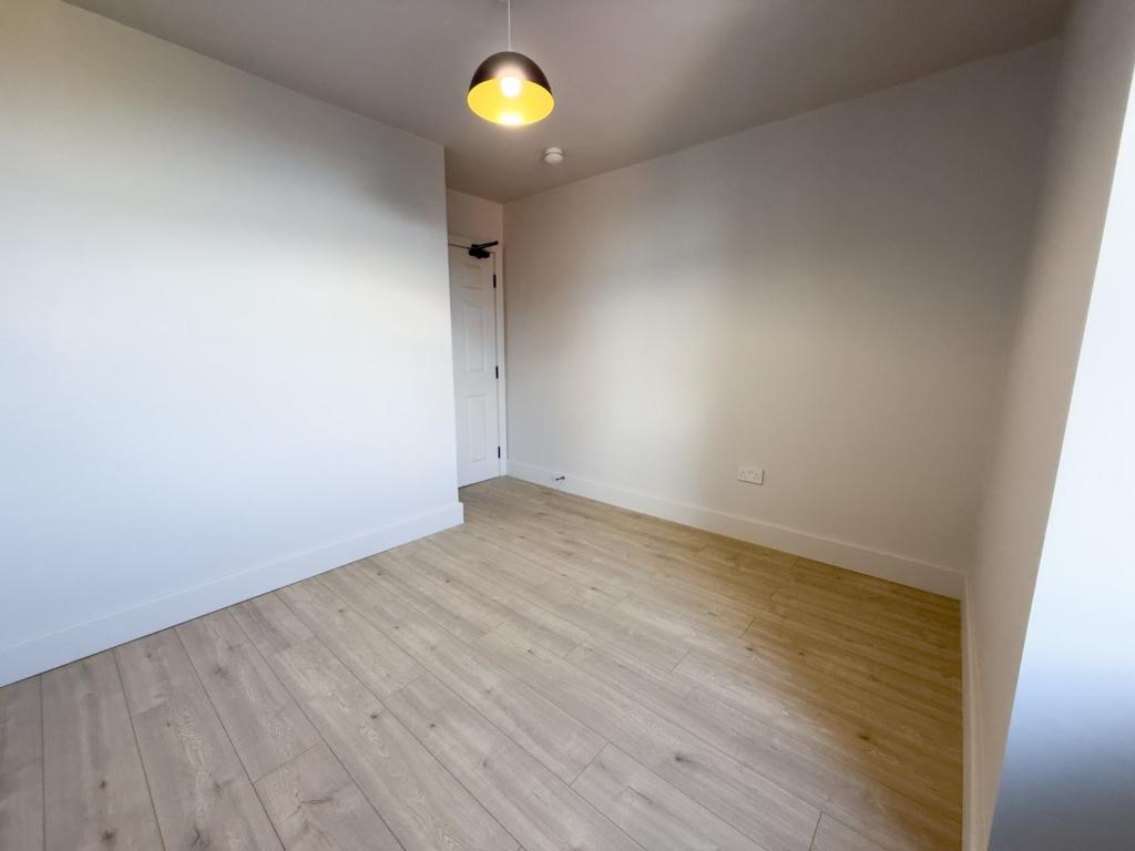 Clean, neutral single bedroom with light wood f...