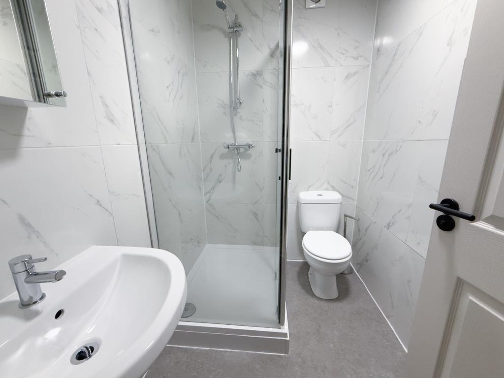 Bright, modern bathroom featuring a walk-in gla...