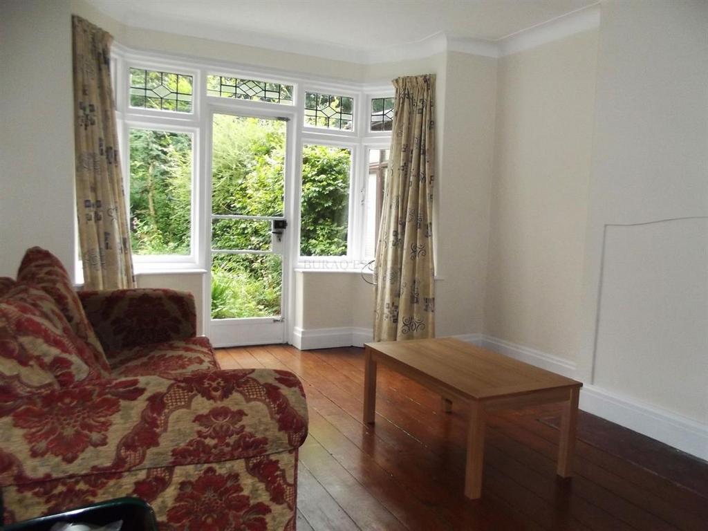 Bright living room with a large bay window and ...