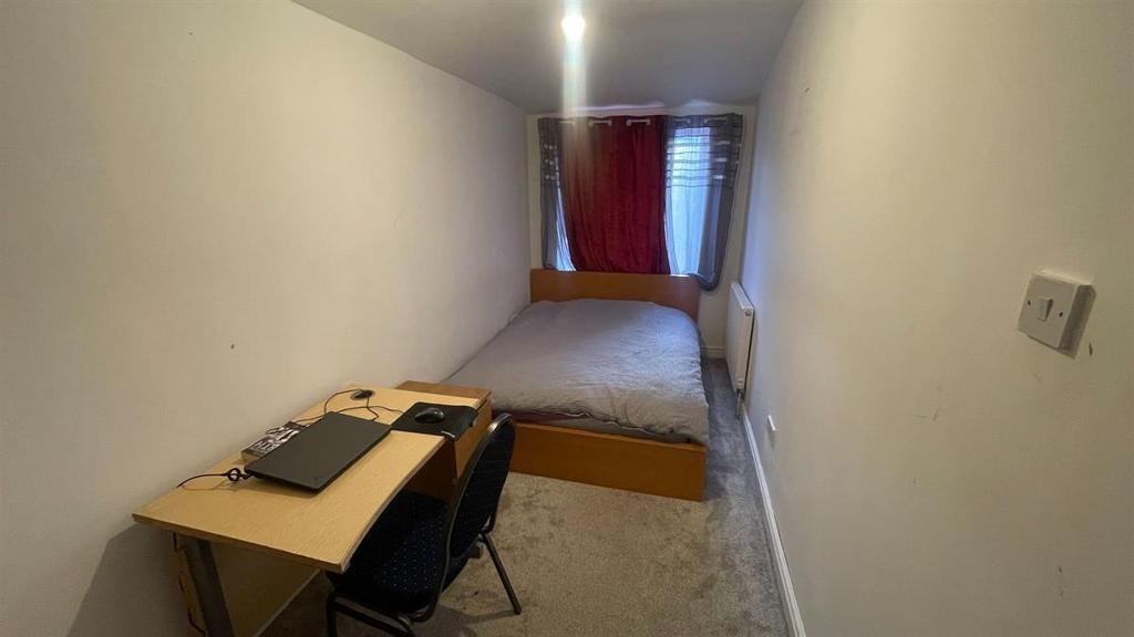 Long, narrow bedroom with a single bed at the f...