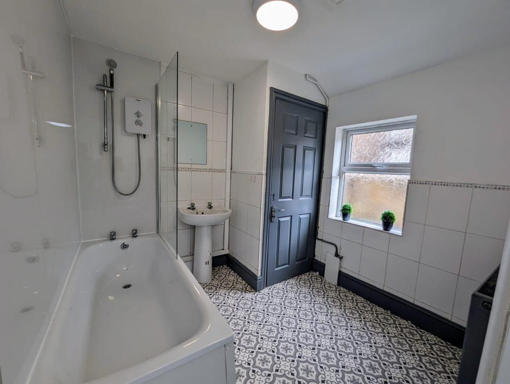 Bright, modern bathroom with patterned tiled fl...