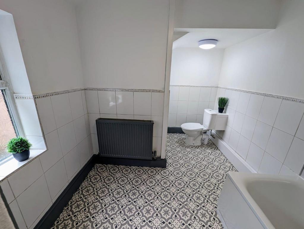 Bright, tiled bathroom with patterned floor til...