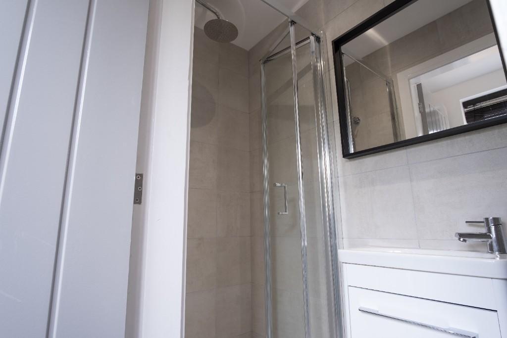 A modern bathroom featuring a glass-enclosed sh...