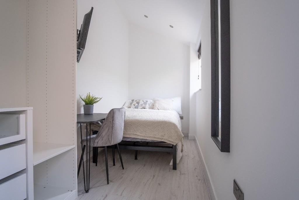 A bright and tidy single bedroom featuring a co...