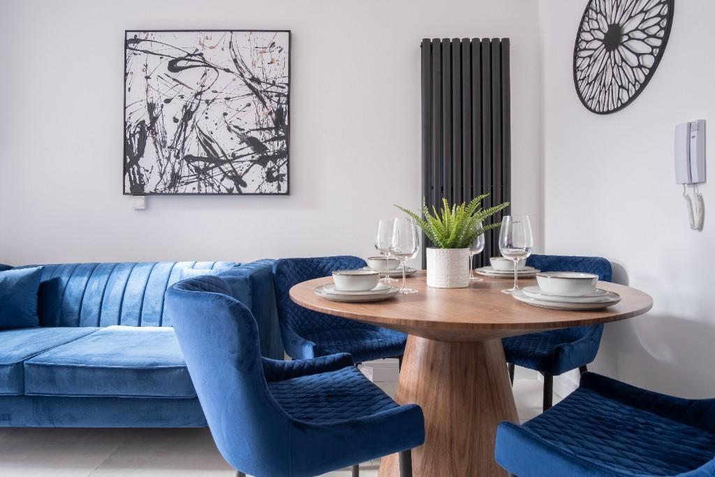 A stylish living room featuring a deep blue vel...