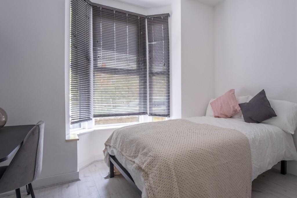 Bright and cozy bedroom featuring a comfortable...