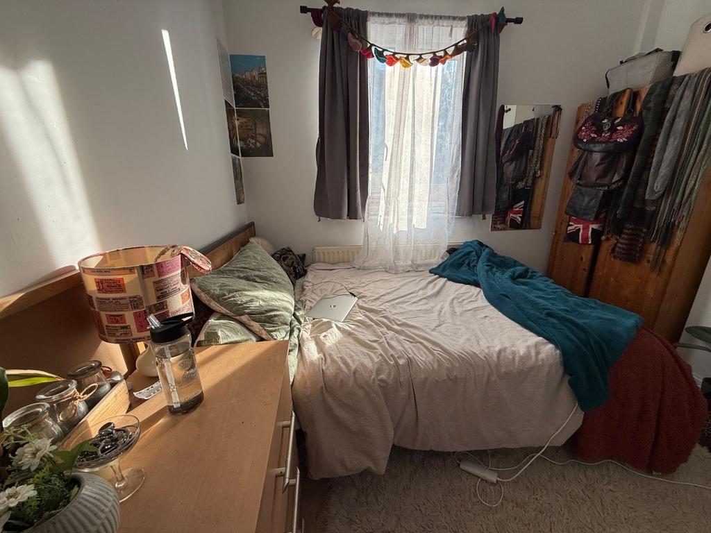 Cozy double bedroom with a large window dressed...