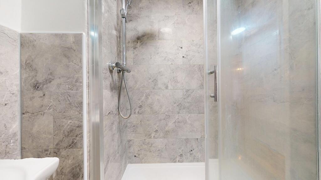 Modern tiled bathroom with a glass-enclosed wal...