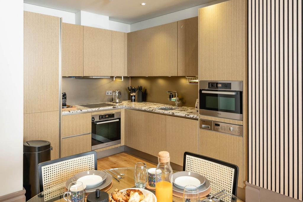 Modern L-shaped kitchen with light wood cabinet...
