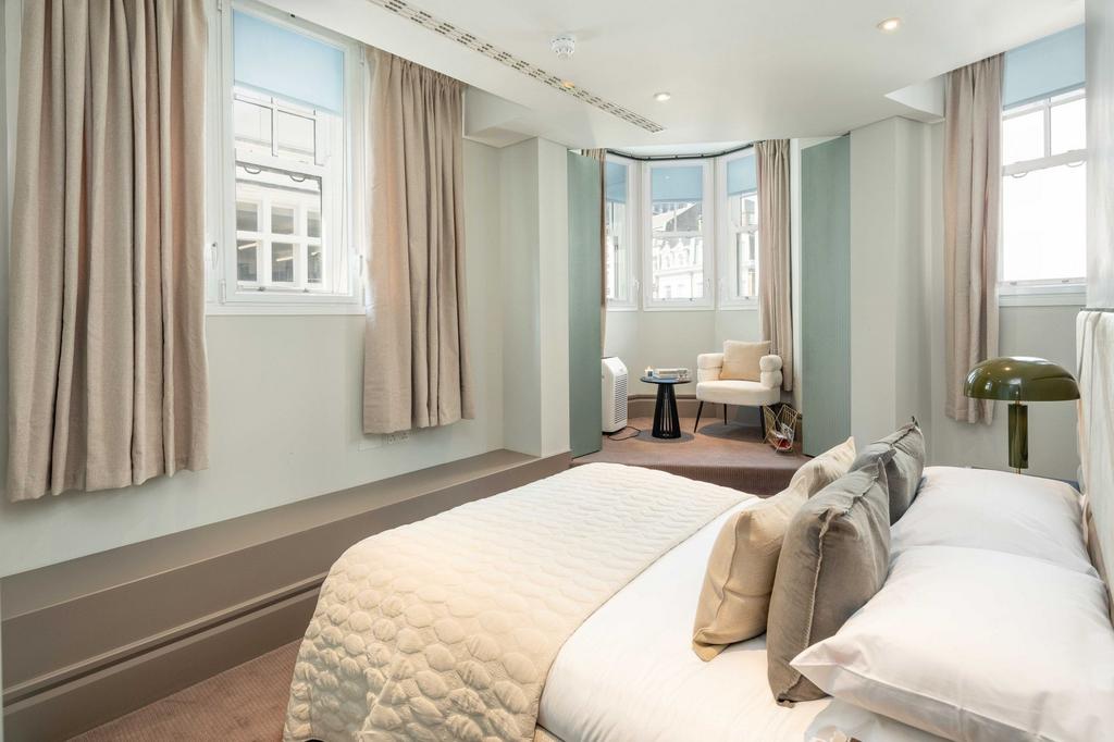 Bright, neatly styled master bedroom with a com...