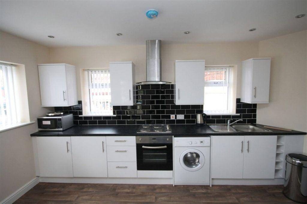 Modern kitchen with sleek white cabinets, black...