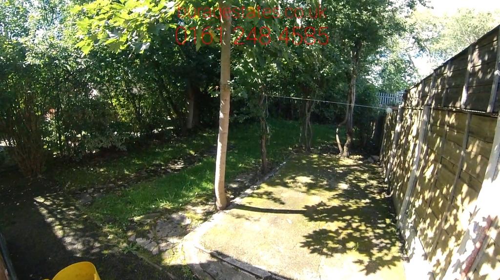 Sunny private garden with mature trees, a paved...