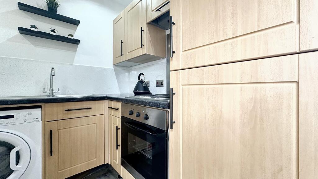 Bright modern kitchen with light wood cabinets,...