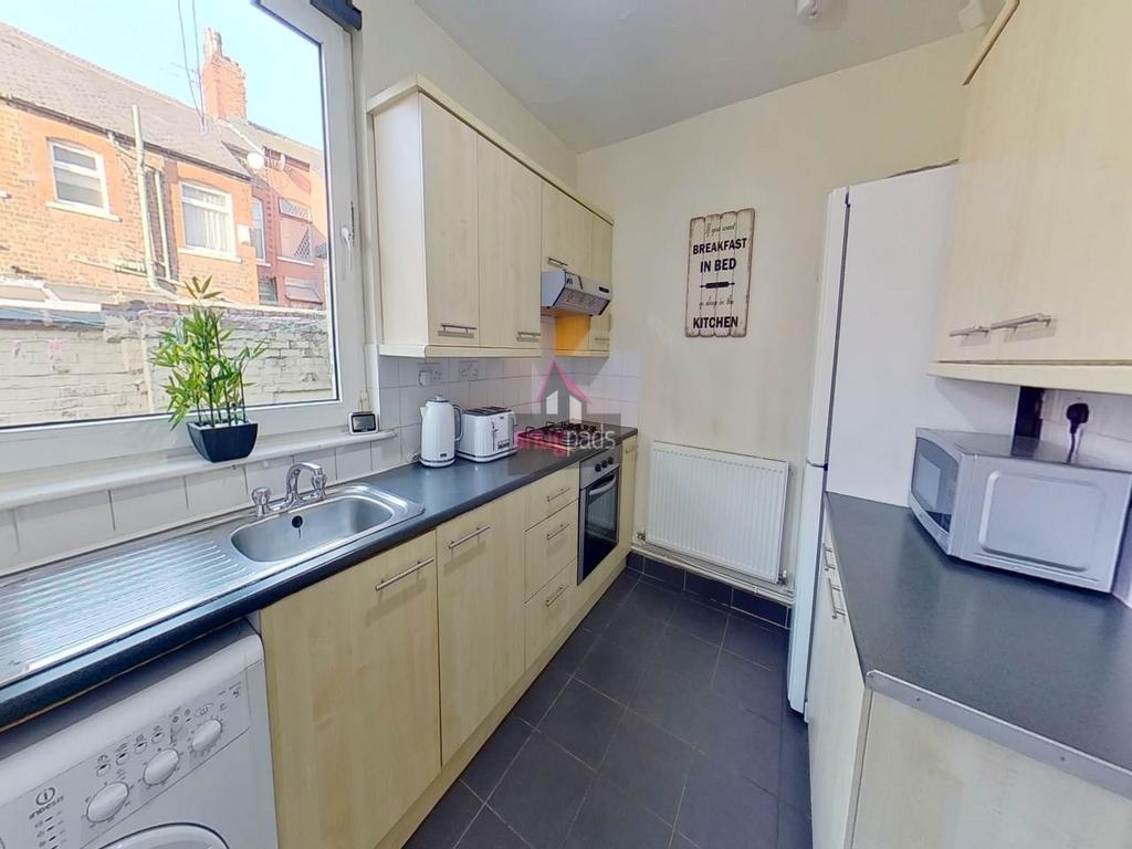 Bright modern galley kitchen with light wood ca...