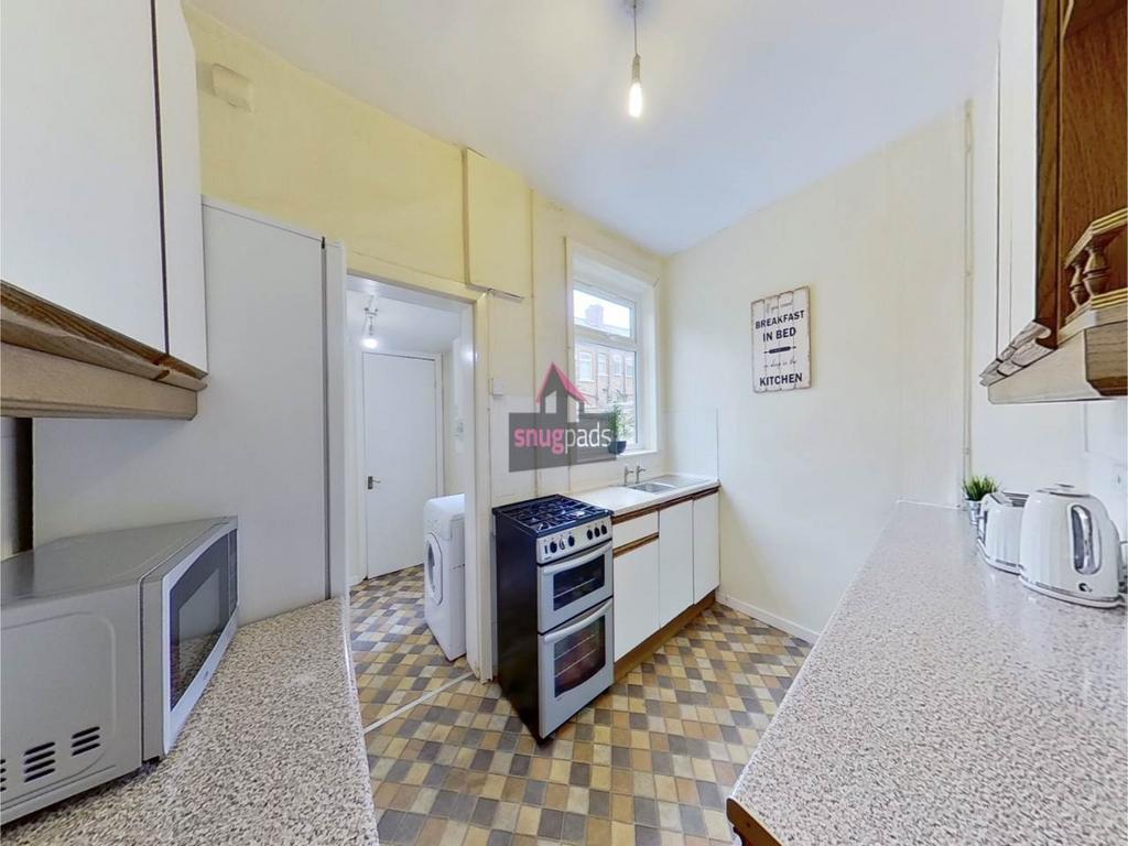 Bright galley-style kitchen with patterned floo...