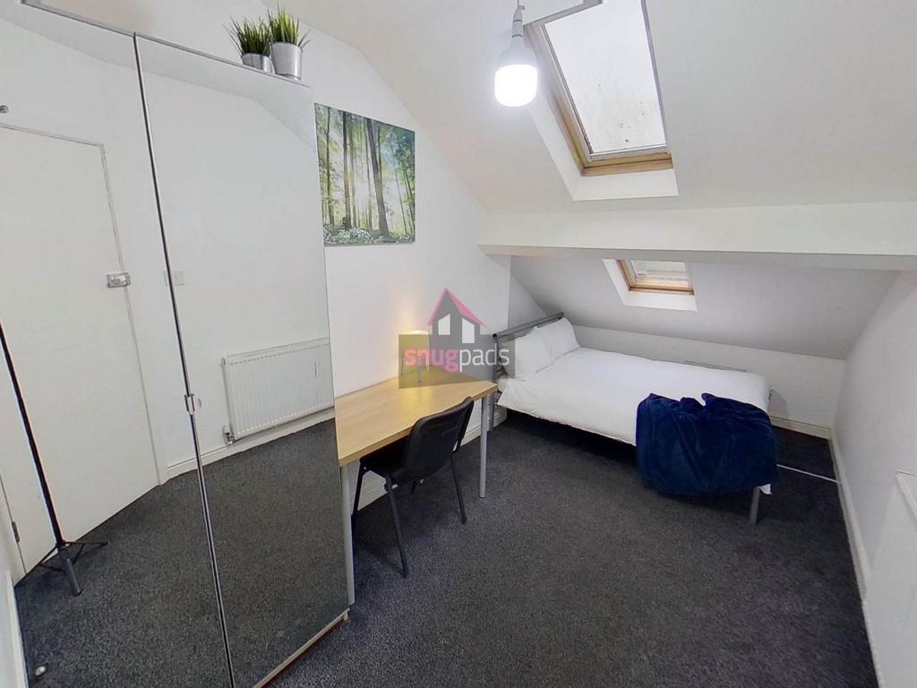 Bright attic-style single bedroom with a skylig...