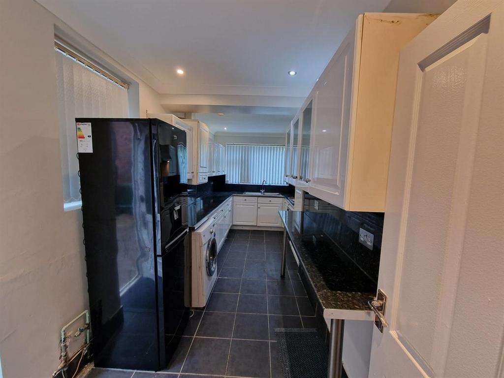 Modern galley kitchen with glossy black worktop...