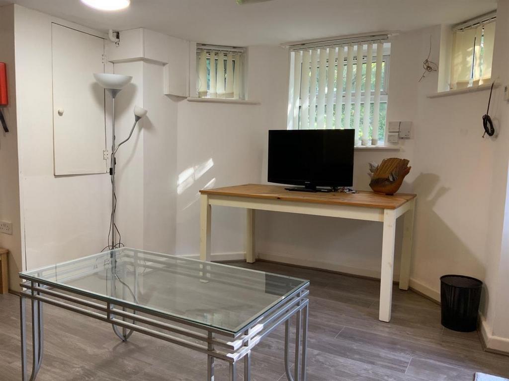 Bright, simply furnished living area with a TV ...