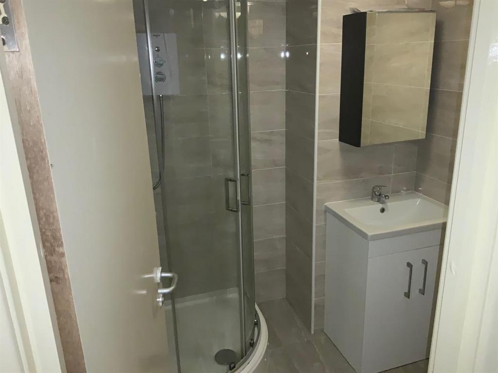 Modern tiled bathroom with a curved glass showe...