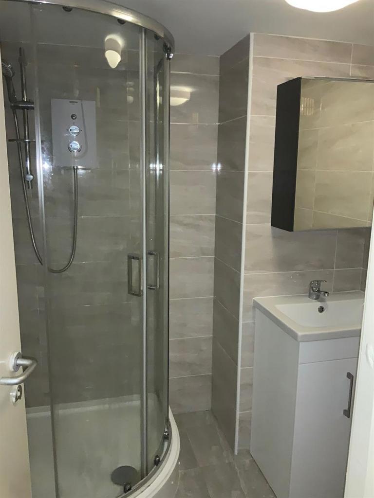 Modern tiled bathroom featuring a curved glass ...