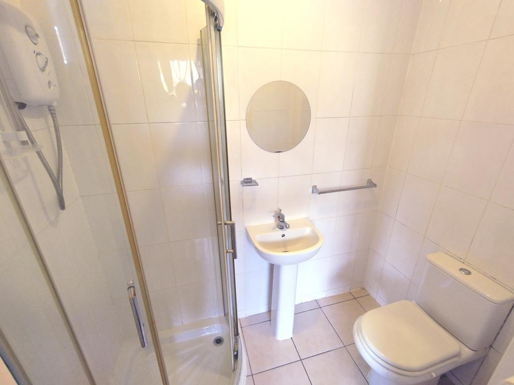 Bright, fully tiled bathroom with a corner show...