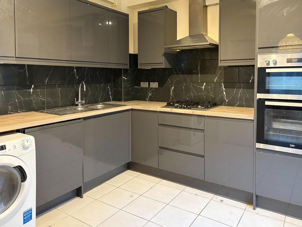 Contemporary fitted kitchen with glossy grey ca...