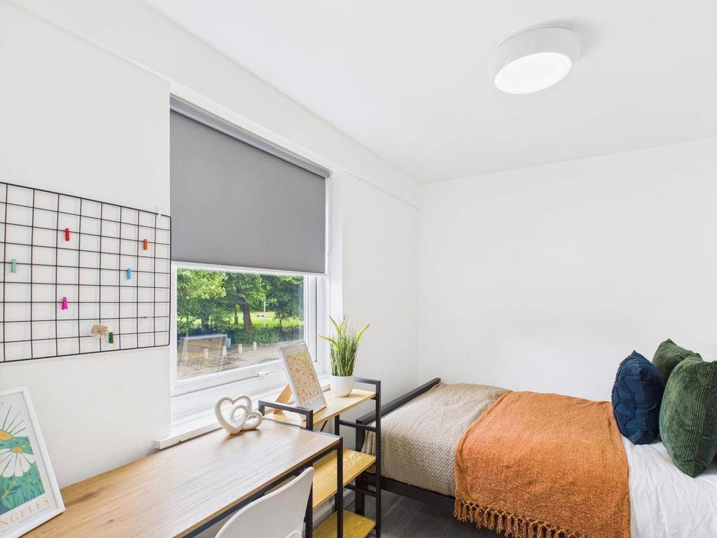 Bright, tidy bedroom with a large desk by the w...