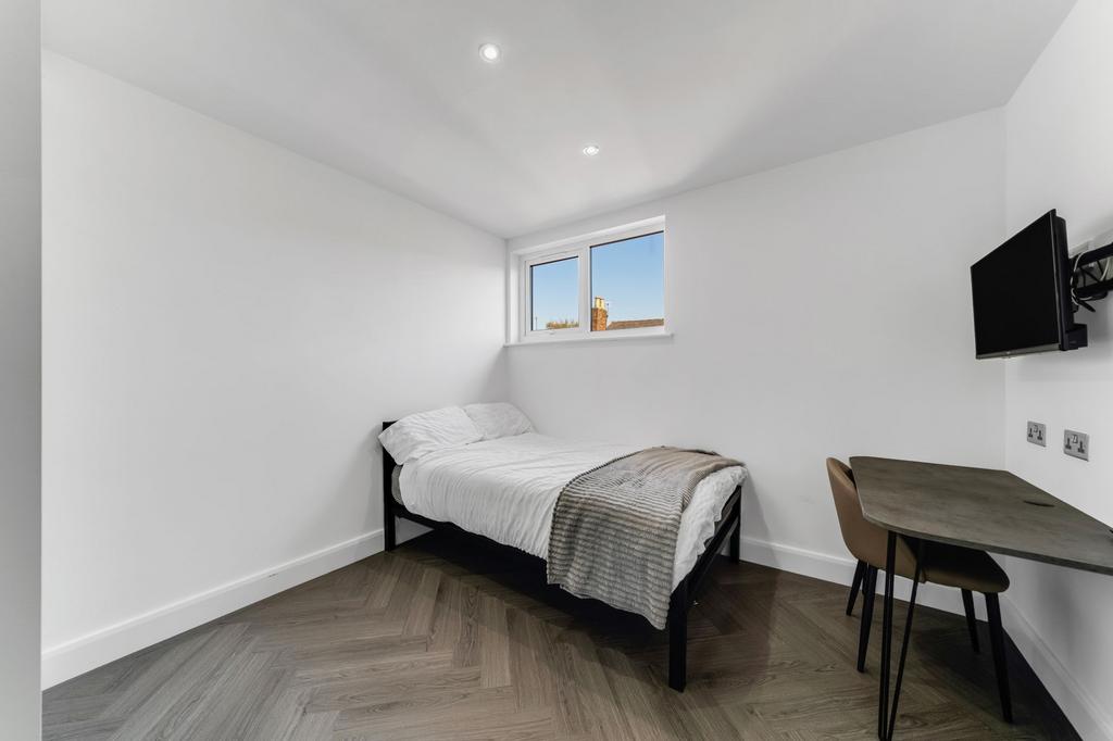 A clean, bright single bedroom featuring a neat...