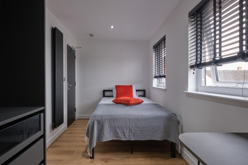 A bright and tidy bedroom featuring two large w...