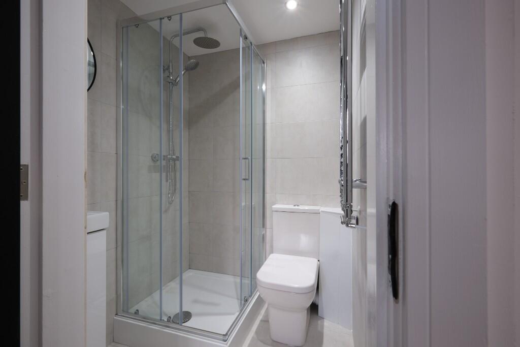 A bright, modern bathroom with a glass-enclosed...