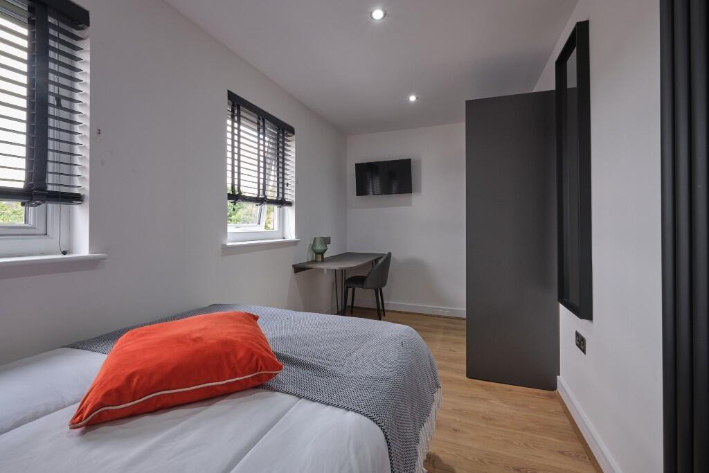 A bright and inviting bedroom featuring a comfo...