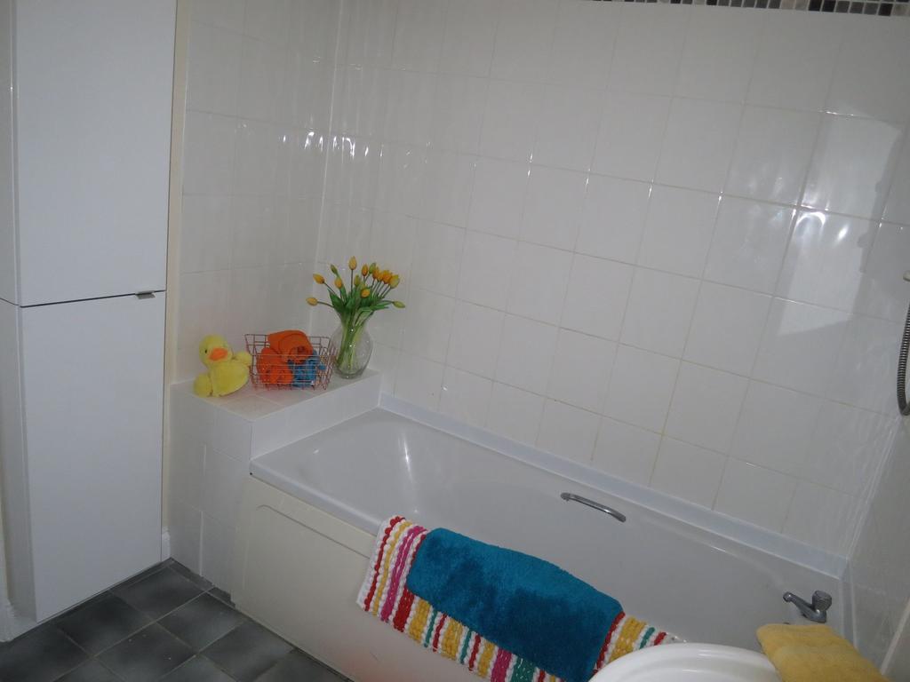 Bright, tiled bathroom featuring a built-in bat...