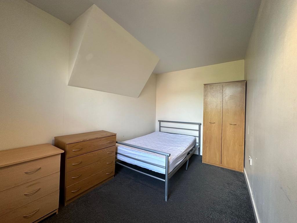 Bright, simply furnished bedroom with a metal d...