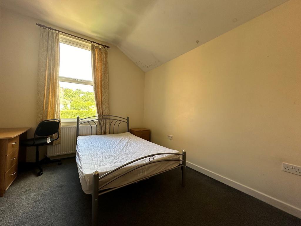 Bright, simply furnished bedroom with a double ...