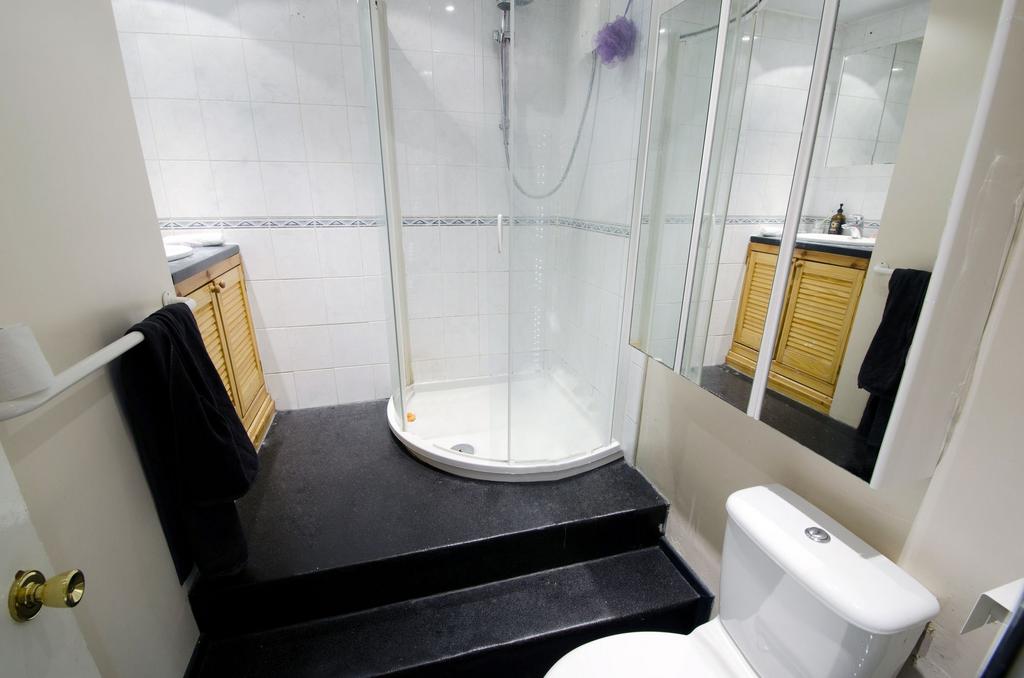 Bright tiled bathroom with a corner glass showe...