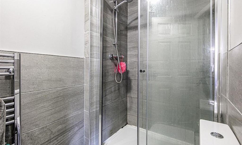Modern tiled bathroom with a glass-enclosed wal...