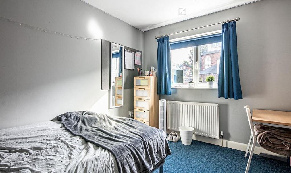 Bright, tidy bedroom with a large window, blue ...