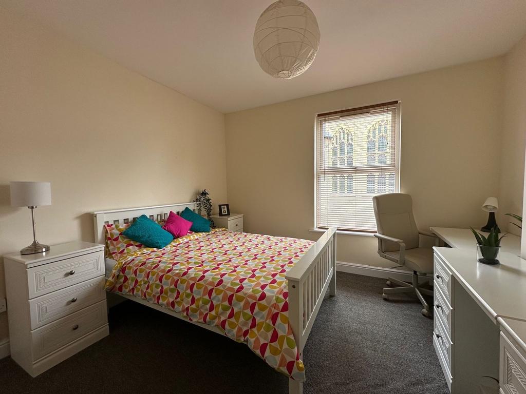 Bright, neatly furnished bedroom with a double ...