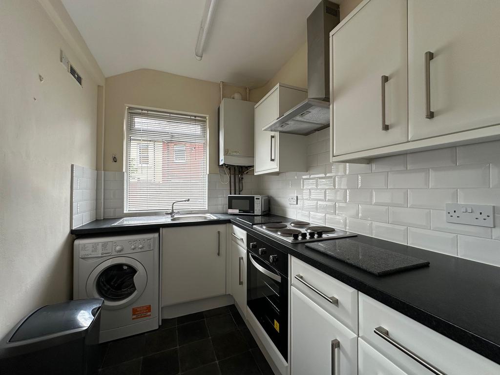 Bright, modern galley kitchen with white cabine...