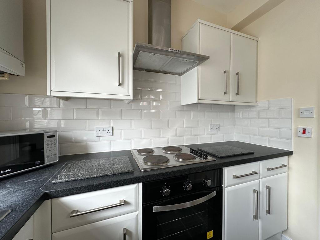 Bright modern kitchen with white cabinets, tile...