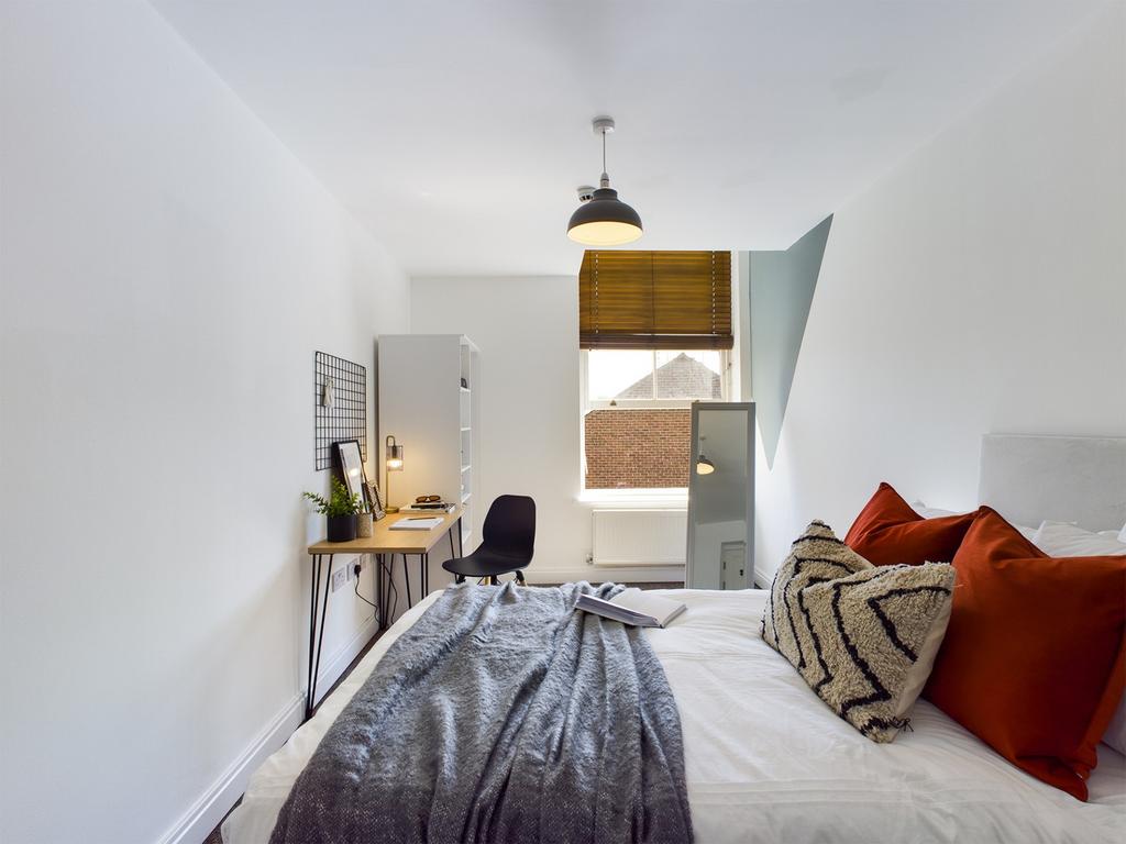 A bright and inviting double bedroom with styli...