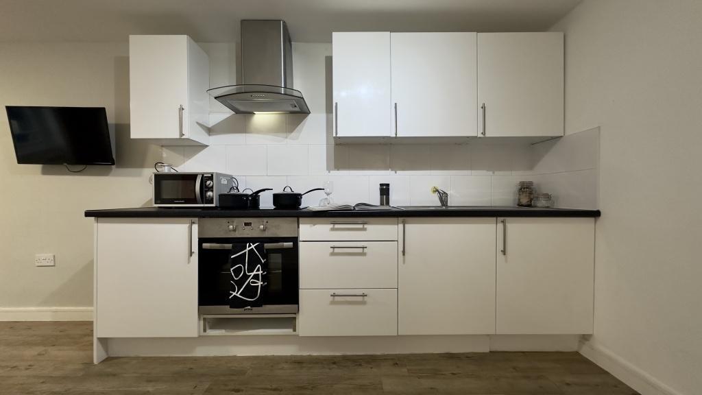 Modern fitted kitchen with white cabinetry, int...