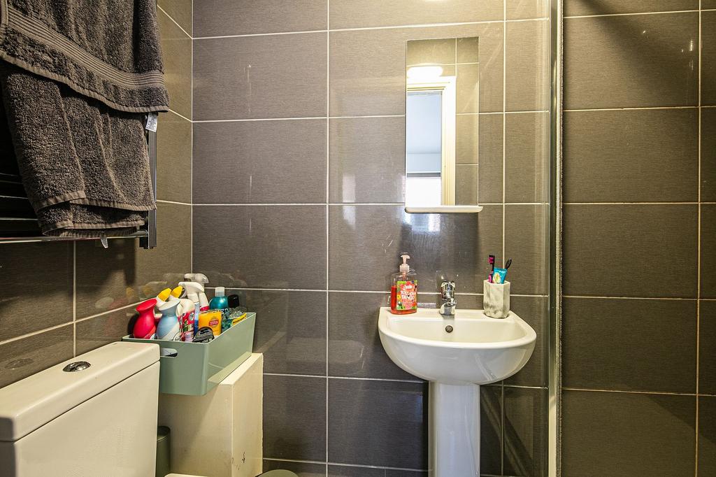 Modern tiled bathroom with a pedestal sink, mir...