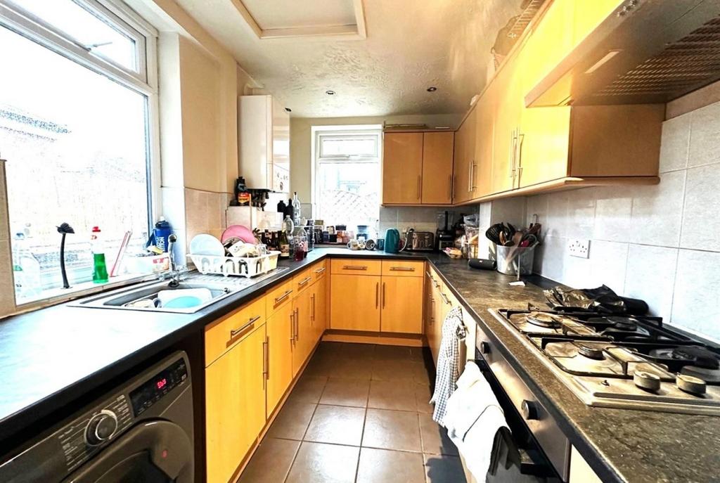 Bright galley kitchen with light wood cabinets,...
