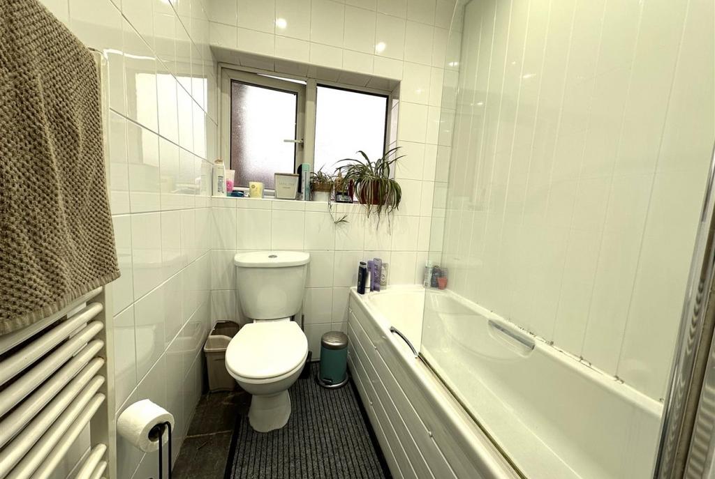 Bright, modern bathroom with white tiled walls,...