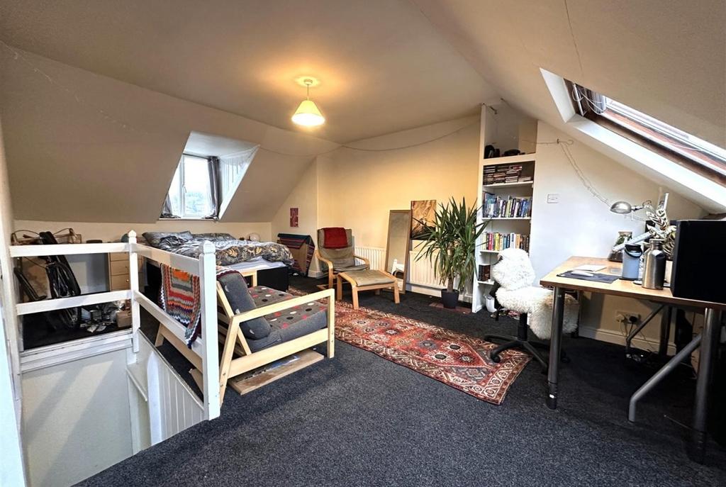 Spacious loft bedroom with sloped skylight wind...