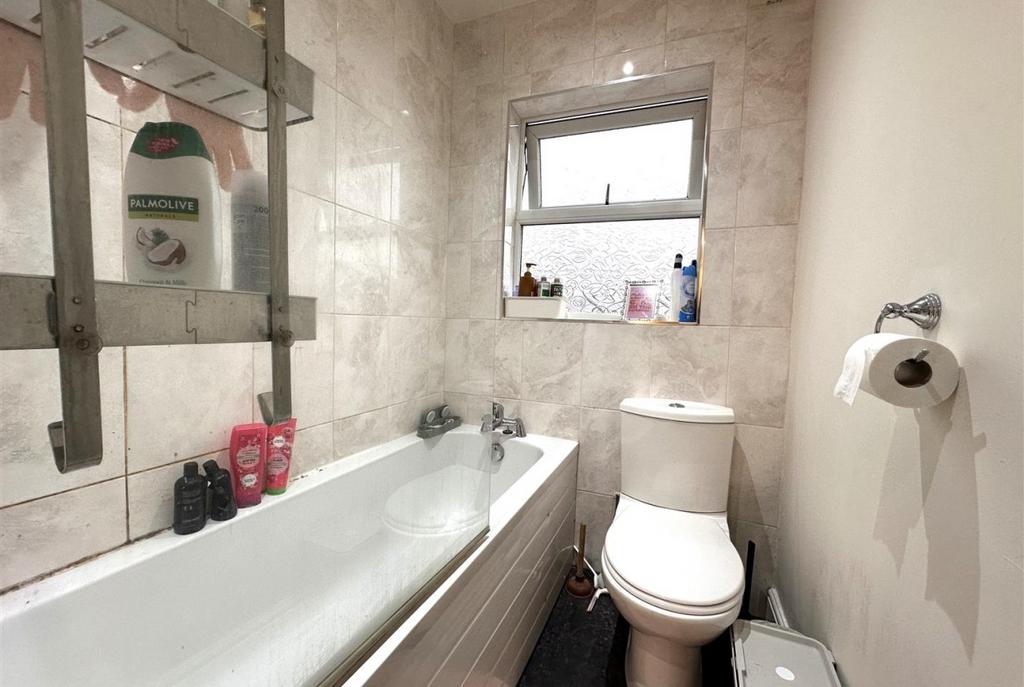 Bright tiled bathroom with a modern white batht...