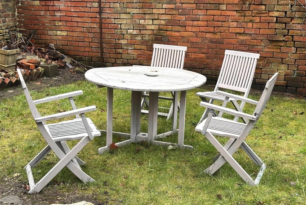 Private walled garden with a round wooden table...