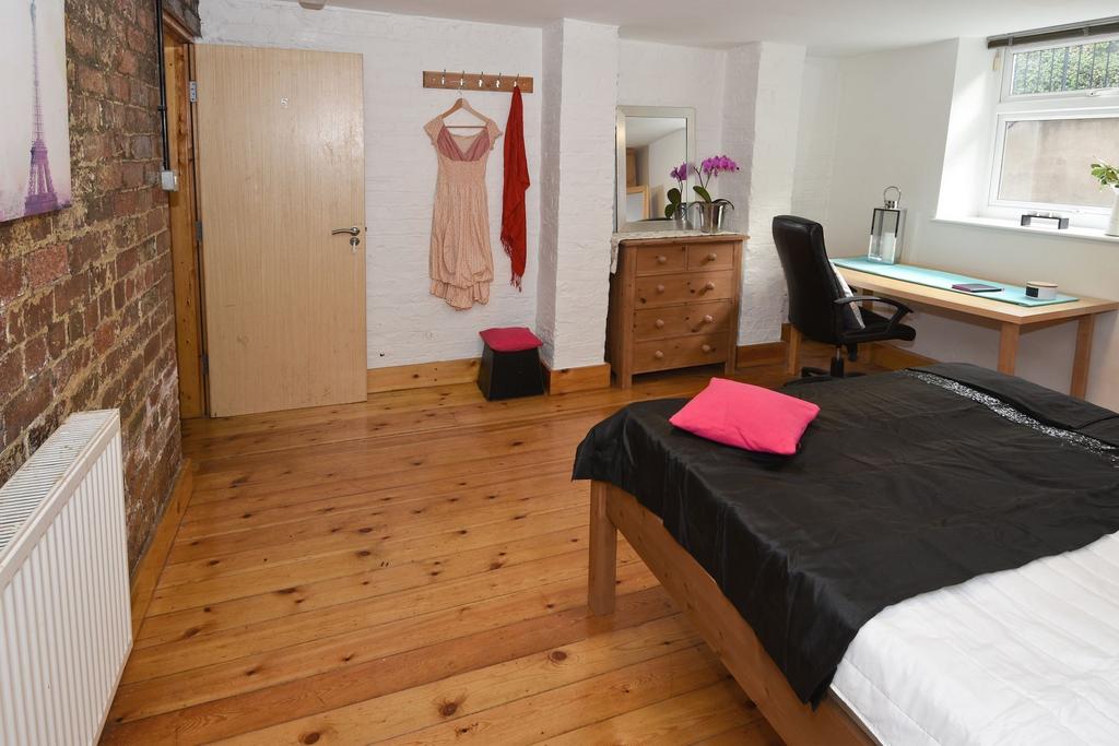 Bright, stylish bedroom with polished wooden fl...